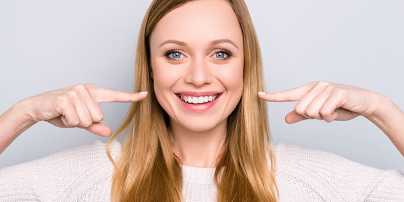smiling woman pointing at her mouth