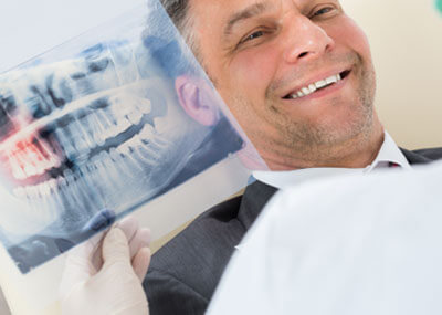 dentist looking at x-rays in front of a dental patient